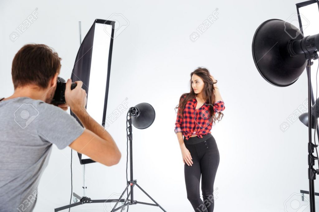 photographer shooting model in professional studio with softboxes