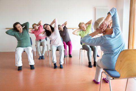class of older women learning chair yoga positions